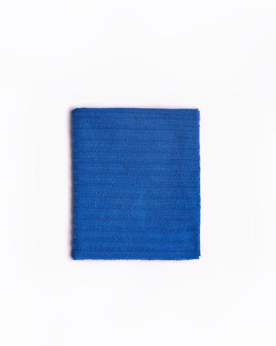 High-quality image of a neatly folded natural linen scarf in a сobalto blue color, showcasing its textured weave. This elegant scarf is perfect for adding a touch of sophistication to any wardrobe, ideal for both casual and formal occasions. Its simple yet stylish design and versatile color make it an essential accessory for fashion-forward individuals